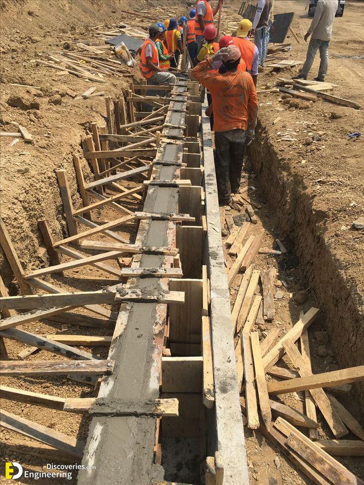 Construction workers performing RCC slab casting at a building site with steel shuttering and safety gear.