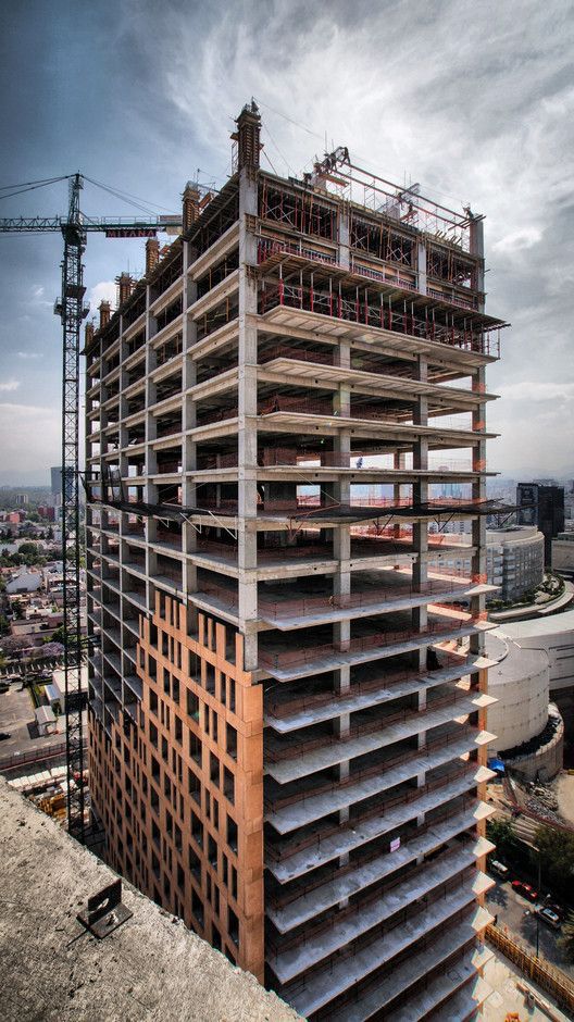 Construction workers performing RCC slab casting at a building site with steel shuttering and safety gear.